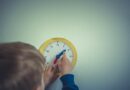 person in blue long sleeve shirt holding white round analog wall clock