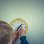 person in blue long sleeve shirt holding white round analog wall clock