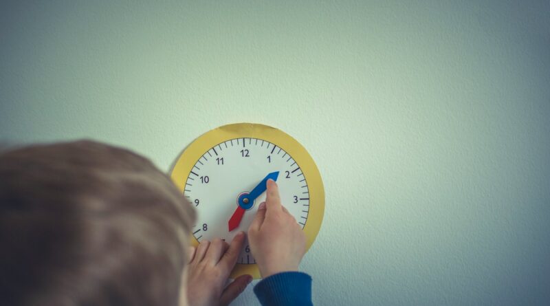 person in blue long sleeve shirt holding white round analog wall clock