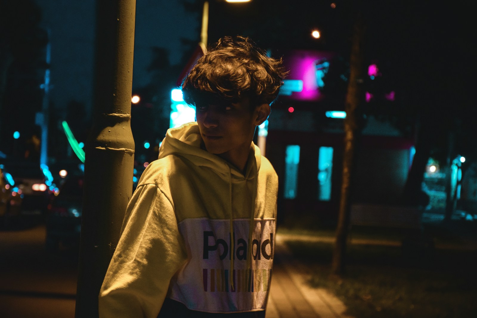 a young man wearing a hoodie standing next to a pole